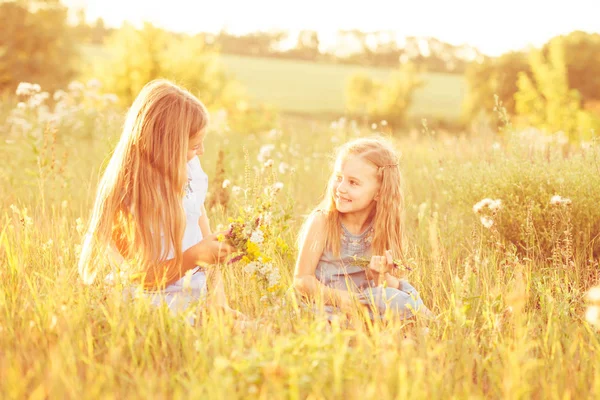 Dos hermanitas tejen coronas de flores — Foto de Stock