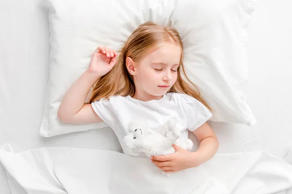 흰색 침대에서 자 고 하는 어린 소녀 — 스톡 사진