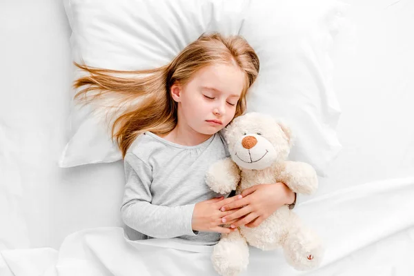 Kleines Mädchen schläft im weißen Bett — Stockfoto