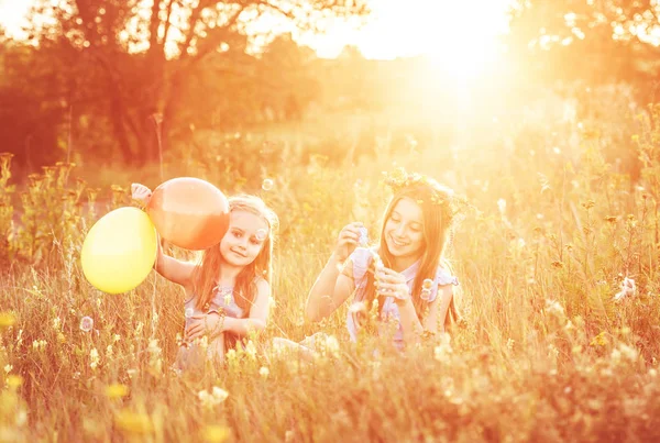 Two little sisters blowing soap bubbles — Stock Photo, Image