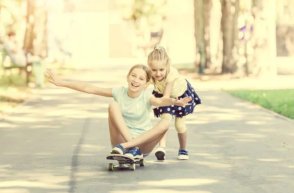 Две маленькие сестры играют на скейтборде — стоковое фото