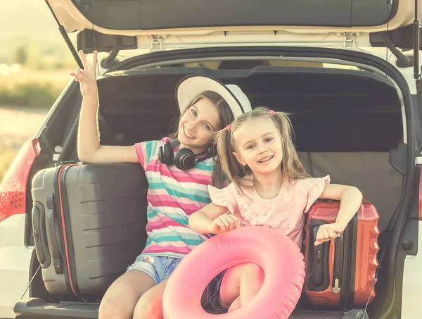 Kleine süße Mädchen im Kofferraum eines Autos mit Koffern — Stockfoto