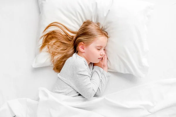 Kleines Mädchen schläft im weißen Bett — Stockfoto