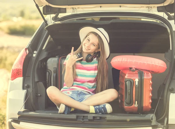 Schattig meisje in de kofferbak van een auto met koffers — Stockfoto