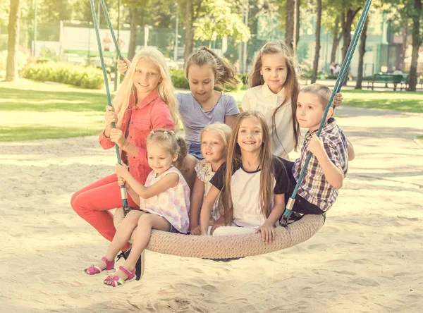 Crianças sorridentes sentadas no baloiço grande — Fotografia de Stock