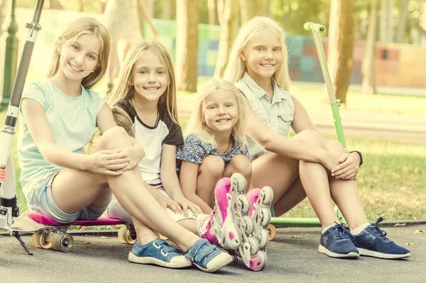 Leende små flickor sitter på marken i parken — Stockfoto