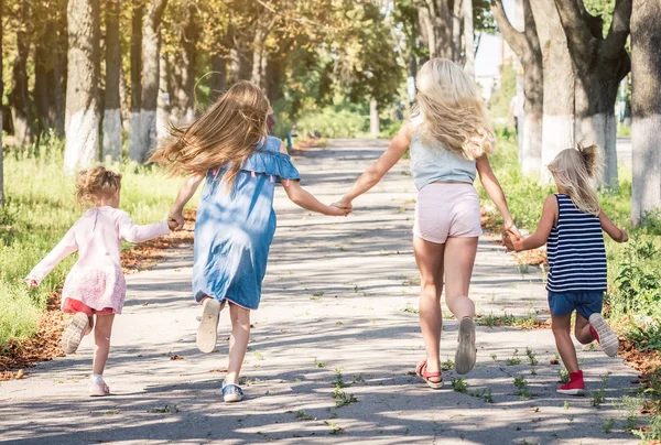 Pequenas garotas sorridentes correndo no beco do outono sol, de mãos dadas — Fotografia de Stock