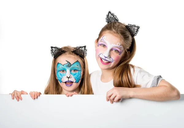 Meninas com artes faciais segurando uma folha para o seu adverisement ou texto isolado — Fotografia de Stock