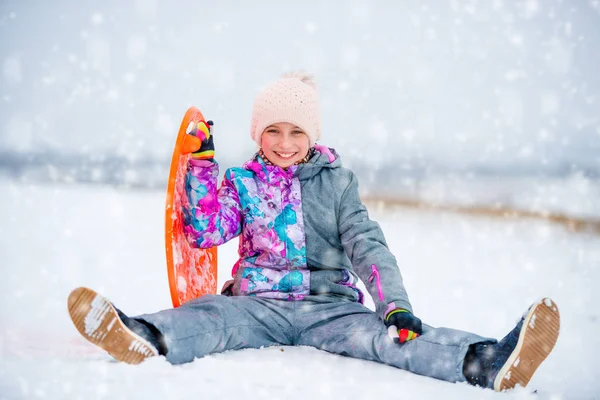 Κορίτσι με πιατάκι έλκηθρο στο χιόνι — Φωτογραφία Αρχείου
