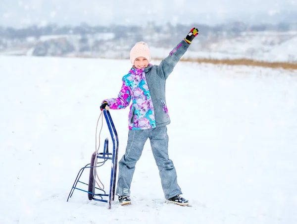 Девушка в лыжном костюме держит сани — стоковое фото