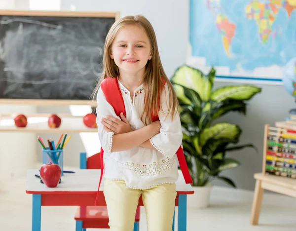 Kleines lächelndes blondes Mädchen steht in der Schulklasse — Stockfoto