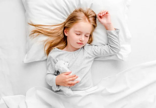 Kleines Mädchen schläft im weißen Bett — Stockfoto