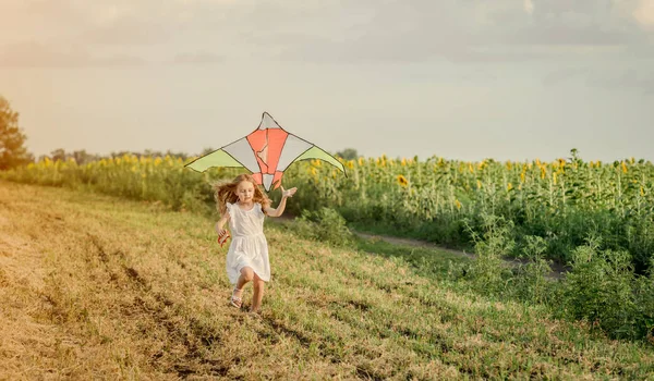 Kleines süßes Mädchen fliegt einen Drachen — Stockfoto