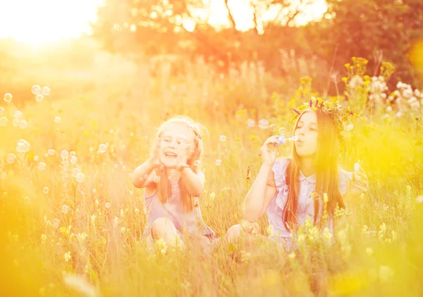 Two little sisters blowing soap bubbles — Stock Photo, Image