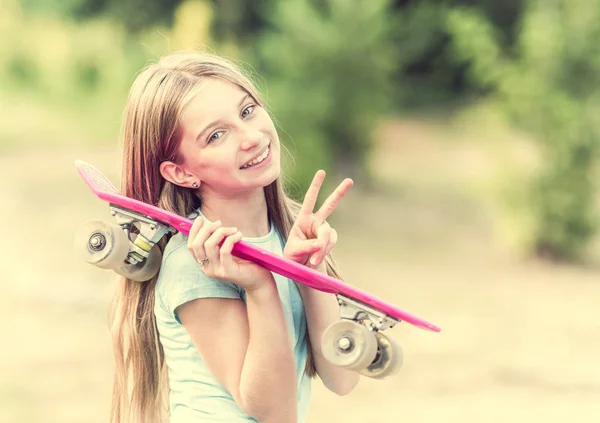 Дівчина-підліток з рожевим скейтбордом посміхається — стокове фото