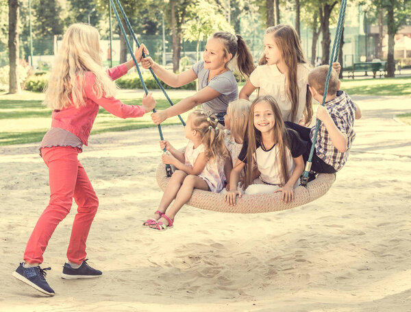 Blond girl swinging little kids