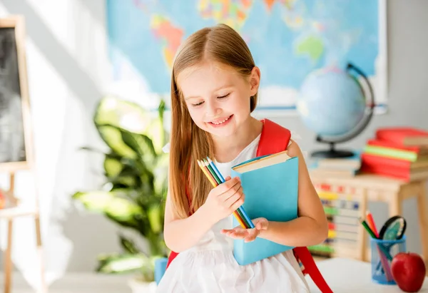 Kleines lächelndes blondes Mädchen steht im Klassenzimmer der Schule — Stockfoto