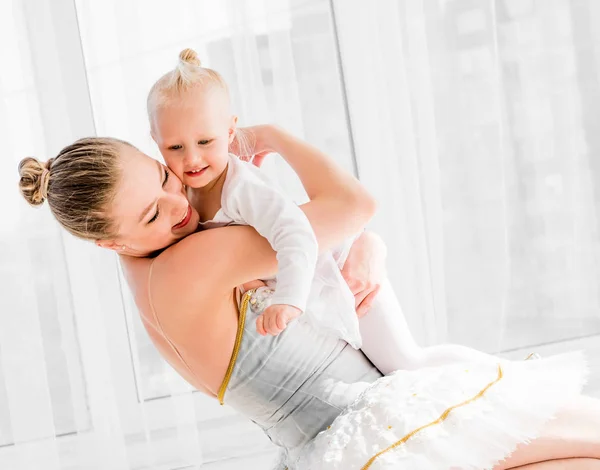 Νεαρή μητέρα αγκαλιάζει την μικρή χαμογελαστή κόρη στο μπαλέτο — Φωτογραφία Αρχείου
