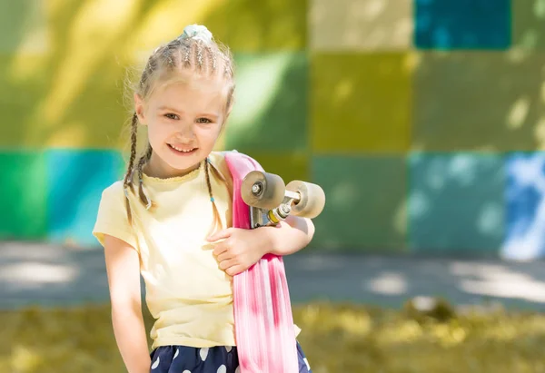 Το χαριτωμένο μικρό κορίτσι με ένα skateboard στον ώμο της — Φωτογραφία Αρχείου
