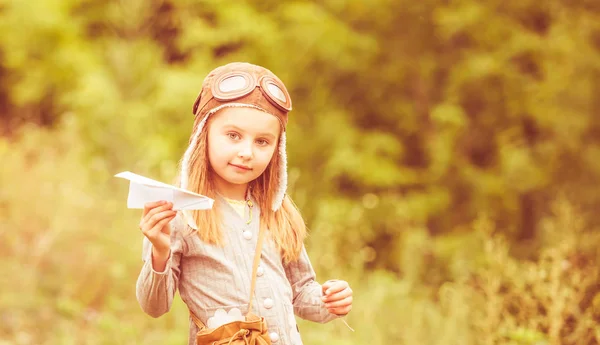 Mignonne petite fille en casque pilote avec avion en papier — Photo