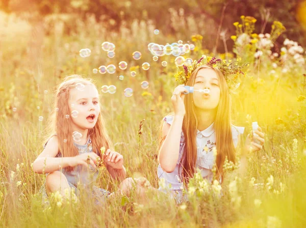 To små søstre som blåser såpebobler – stockfoto