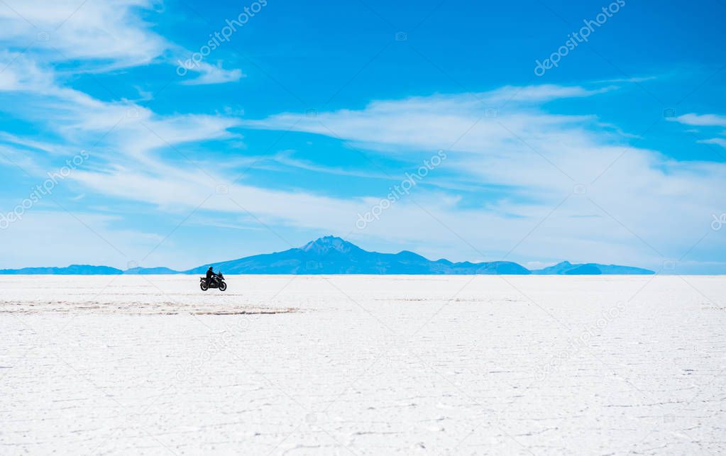 Sunshine scenery of Salar de Uyuni in Bolivia with biker riding over