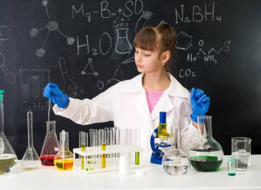 Kimya laboratuarındaki küçük zeki kız bir deney yapıyor.