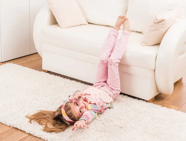 Smiling girl is stretching in living room — Stock Photo, Image