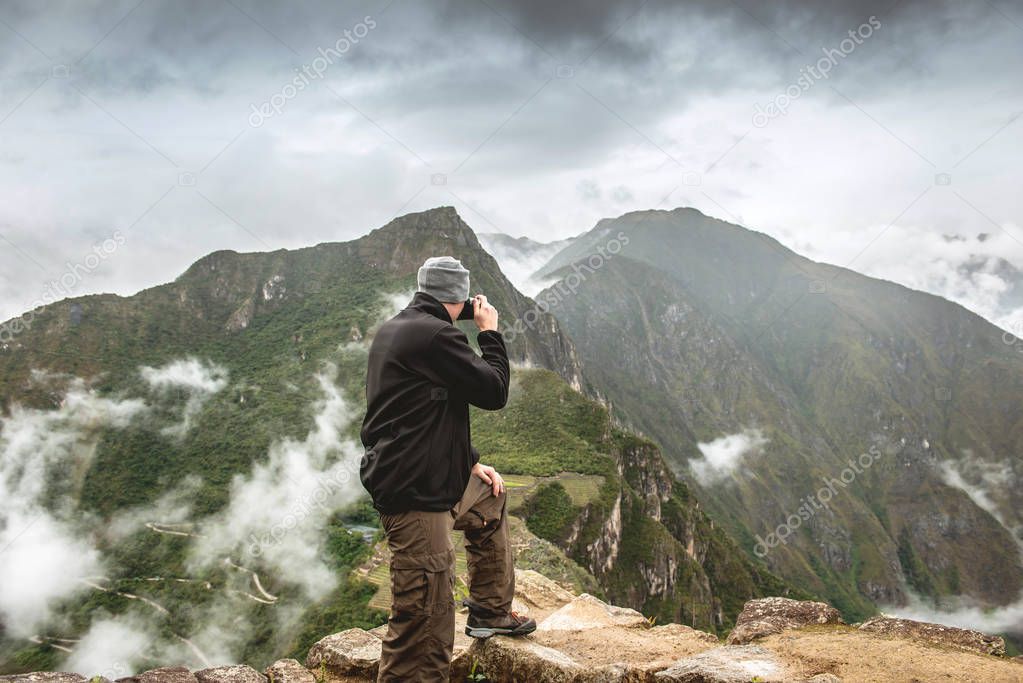 Standing man taking pictures of Machu Picchu