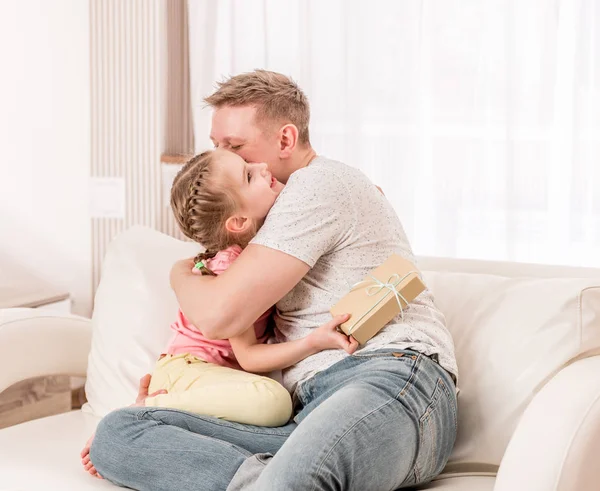 Dochter verrassing vader met cadeau en knuffel — Stockfoto