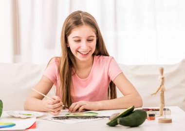 Yeşil avokado çizerken kız gülümsüyor