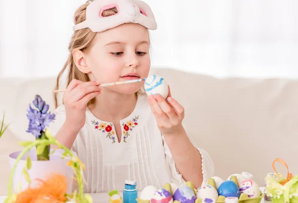 Girl coloring eggs in mask — Stock Photo, Image