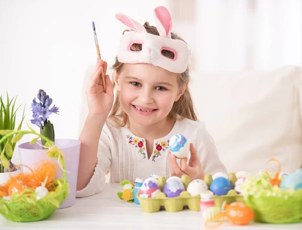 Girl coloring eggs in mask — Stock Photo, Image