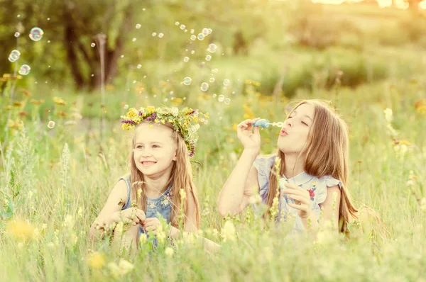 Duas irmãs pequenas soprando bolhas de sabão — Fotografia de Stock