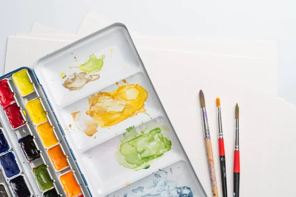 Stained paintbox with brushes — Stock Photo, Image