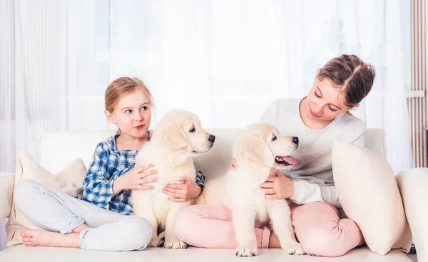 Gülümseyen kız kardeşler köpek yavrularıyla oturuyor — Stok fotoğraf