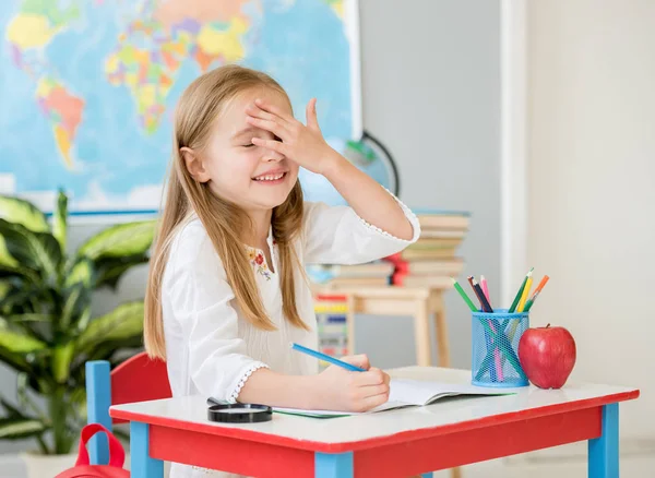 Kleines lächelndes blondes Mädchen machte einen Fehler beim Schreiben in der Schulklasse — Stockfoto