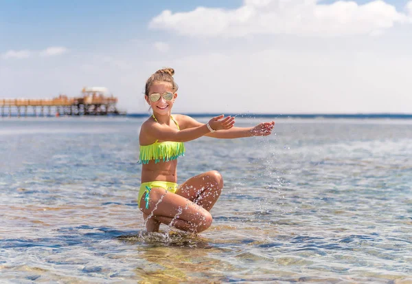 Funny girl jouer avec de l'eau à la plage — Photo