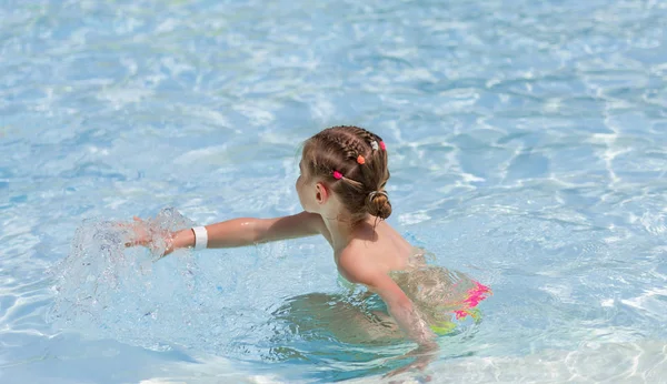 Klein meisje spelen in transparant water — Stockfoto