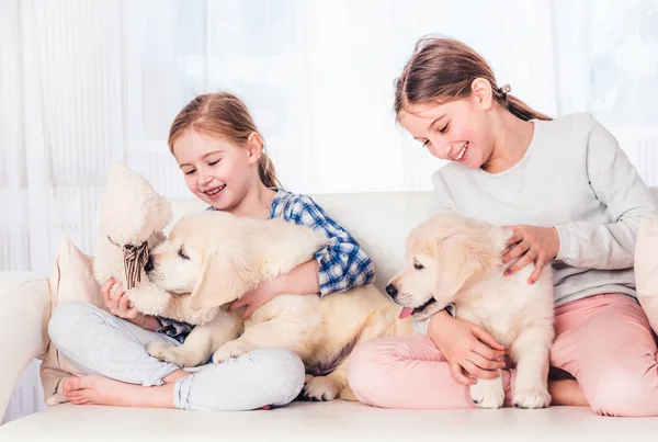 Sœurs souriantes assises avec des chiots — Photo