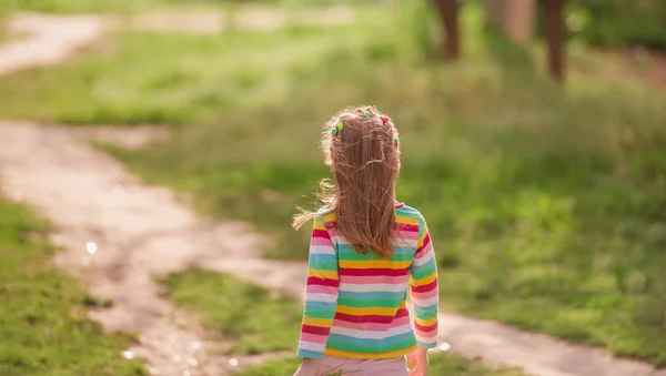 Little girl going away at road — Stock Photo, Image