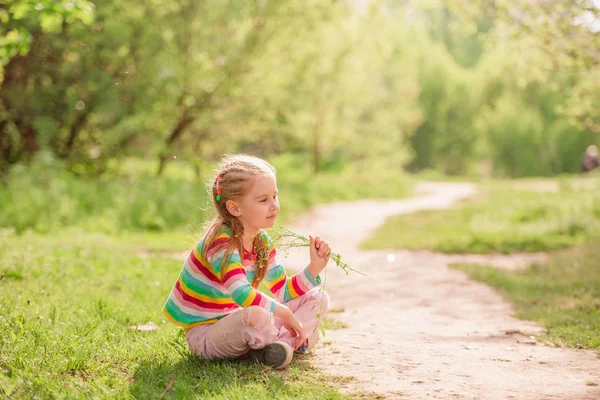 Kind zittend in de buurt van de weg met bloem — Stockfoto