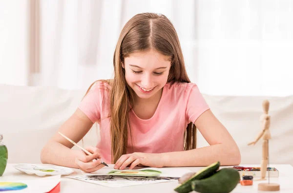 Menina sorri ao desenhar abacate verde — Fotografia de Stock
