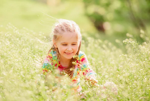 Child resting on green field — Stock Photo, Image