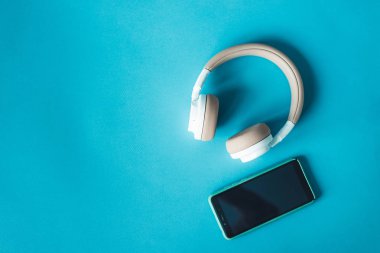 Mavi yüzeyde akıllı telefon ve heaphone'lar