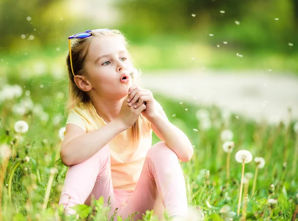 Leuk meisje spelen met paardebloemen — Stockfoto