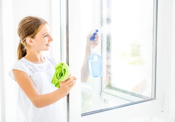 Chica adolescente ventana de limpieza con spray — Foto de Stock