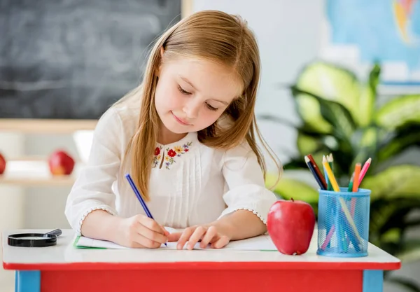 Küçük sarışın kız okulu sınıfta classwork yazma — Stok fotoğraf