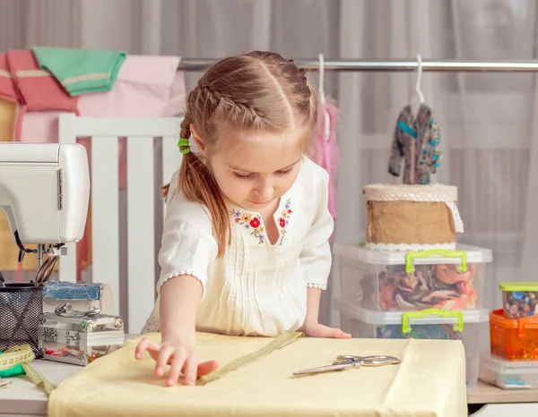 Klein meisje in een workshop naaien — Stockfoto