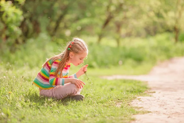 Dziecko siedzi w pobliżu drogi z kwiatem — Zdjęcie stockowe